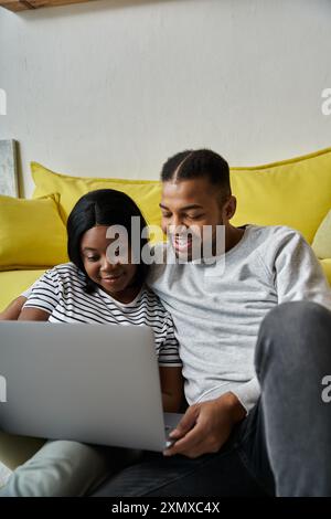 Un couple afro-américain aimant aime passer du temps ensemble tout en utilisant un ordinateur portable à la maison. Banque D'Images