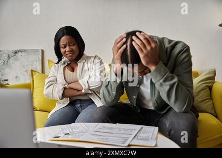 couple afro-américain sur le canapé, homme en détresse, femme concernée. Banque D'Images