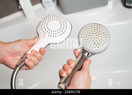 Remplacement d'une vieille pomme de douche par une nouvelle. Mauvaise qualité de l'eau et accumulation de calcaire sur les appareils de plomberie. Remplacement et entretien périodiques du cl Banque D'Images