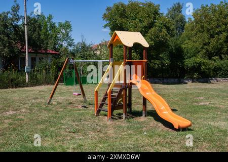 Terrain de jeux pour enfants glisse et balançoire dans un petit village de campagne en gros plan sur la journée ensoleillée d'été Banque D'Images