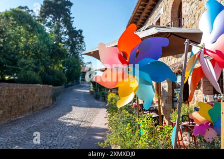 Gros plan d'une roue à épingles multicolore vibrante qui tourne dans un cadre extérieur ensoleillé. L'arrière-plan dispose de parasols de patio et d'un charmant jardin, addin Banque D'Images