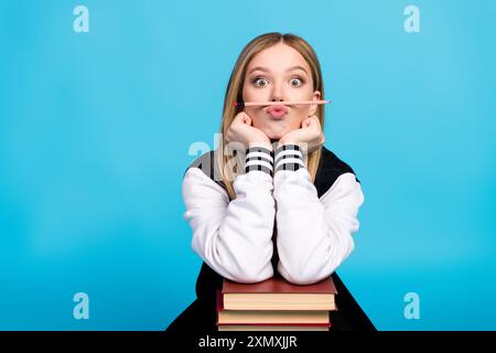 Photo de mignonne belle fille d'université joyeuse porter des vêtements à la mode souffler lèvres moustache isolé sur fond de couleur bleue Banque D'Images