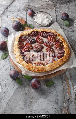 Délicieuse galette de prunes à tarte ouverte avec des amandes gros plan sur une planche de bois sur la table. Horizontal Banque D'Images