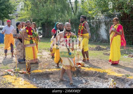 Un homme hindou pieux portant un collier de guirlande marche pieds nus sur des charbons brûlants au Thimithi Fire Walking Festival en Jamaïque, Queens, NY Banque D'Images