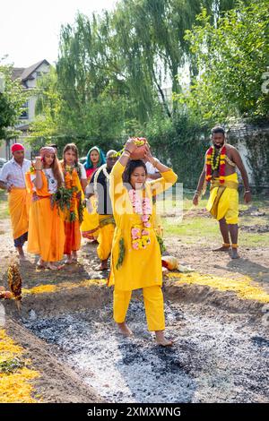 Un fidèle hindou pieux marche pieds nus sur des charbons brûlants au Thimithi Fire Walking Festival au Arya Spiritual Grounds à Jamaica, Queens, NY Banque D'Images