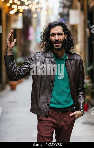 Homme en colère avec de longs cheveux levant la main agressivement se disputant dans la rue Banque D'Images