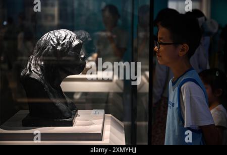 Haikou, province chinoise de Hainan. 30 juillet 2024. Un enfant visite une réplique d'un crâne de l'homme de Pékin lors de l'exposition culturelle du site Zhoukoudian au Musée Hainan à Haikou, dans la province de Hainan au sud de la Chine, le 30 juillet 2024. L’exposition culturelle du site Zhoukoudian s’est ouverte mardi avec un total de 139 pièces d’exposition du musée du site Zhoukoudian à Pékin. Crédit : Guo Cheng/Xinhua/Alamy Live News Banque D'Images