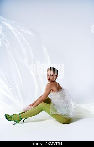 Une femme portant une tenue verte et une robe en papier bulle recyclé pose dans un cadre de studio. Banque D'Images