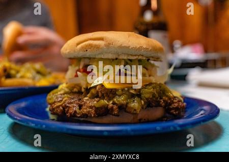 Vue rapprochée du hamburger avec fromage, laitue et tomate sur plaque bleue dans le dîner local. Banque D'Images