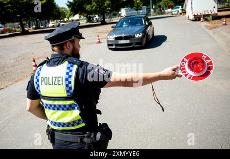 Hambourg, Allemagne. 30 juillet 2024. S'IL VOUS PLAÎT PIX LE SIGNE D'IDENTIFICATION - Un policier arrête une voiture lors d'un contrôle pour des défauts techniques dans le district de Bahrenfeld. Lors d'un contrôle à grande échelle, la police a vérifié le respect des règles de sécurité routière. Crédit : Daniel Bockwoldt/dpa - ATTENTION : les plaques d'immatriculation ont été pixelisées pour des raisons légales/dpa/Alamy Live News Banque D'Images