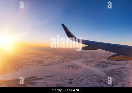 Avion volant bas au-dessus de montagnes enneigées et se préparant à atterrir à l'aéroport, vue depuis la fenêtre de l'avion de la turbine d'aile et de l'horizon Banque D'Images