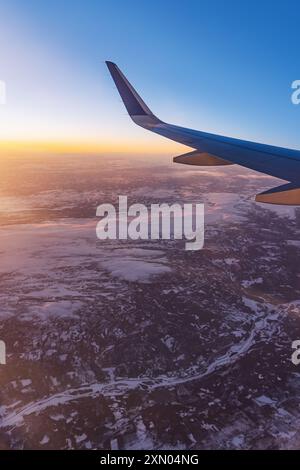 Avion volant bas au-dessus de montagnes enneigées et se préparant à atterrir à l'aéroport, vue depuis la fenêtre de l'avion de la turbine d'aile et de l'horizon Banque D'Images