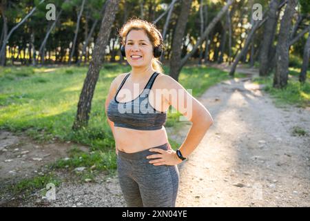 Femme gras et sports. Fille faisant de l'exercice pour la perte de poids dans l'air frais et rire dans l'appareil photo après l'entraînement. Banque D'Images