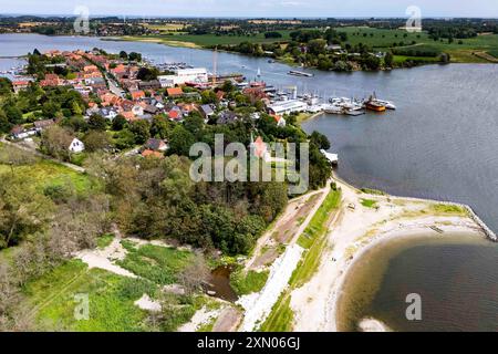 Arnis, Allemagne. 24 juillet 2024. Le soleil brille sur le village Schlei d'Arnis, qui a été durement touché par la forte onde de tempête de la mer Baltique à l'automne 2023. La digue a été brisée par la crue sur une longueur de 60 mètres. Tout le long de la côte de l'État, des digues et des installations portuaires ont été endommagées ou détruites, et des maisons, des campings et des hôtels ont été dévastés. Le gouvernement de l'État a estimé les dégâts à environ 200 millions d'euros. (Vue aérienne avec drone) crédit : Frank Molter/dpa/Alamy Live News Banque D'Images