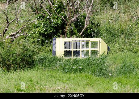 Arnis, Allemagne. 24 juillet 2024. Une vieille cabine téléphonique se trouve sur les rives du Schlei, inondé lors de la grave onde de tempête de la mer Baltique à l'automne 2023. La digue à Arnis a été percée sur une longueur de 60 mètres. Tout le long de la côte, des digues et des installations portuaires ont été endommagées ou détruites, et des maisons, des campings et des hôtels ont été dévastés. Le gouvernement de l'État a estimé les dégâts à environ 200 millions d'euros. Crédit : Frank Molter/dpa/Alamy Live News Banque D'Images