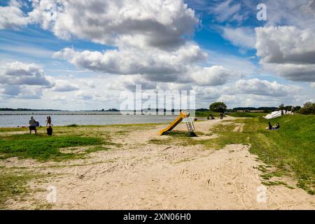 Arnis, Allemagne. 24 juillet 2024. Un toboggan se dresse sur les rives du Schlei, inondé lors de la grave onde de tempête de la mer Baltique à l'automne 2023. La digue à Arnis a été percée sur une longueur de 60 mètres. Tout le long de la côte, des digues et des installations portuaires ont été endommagées ou détruites, et des maisons, des campings et des hôtels ont été dévastés. Le gouvernement de l'État a estimé les dégâts à environ 200 millions d'euros. Crédit : Frank Molter/dpa/Alamy Live News Banque D'Images