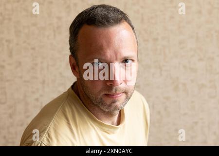 Portrait studio d'un jeune homme européen sérieux et non rasé en t-shirt jaune, photo en gros plan Banque D'Images