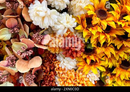 fleurs artificielles, y compris tournesols, chrysanthèmes, et diverses feuilles et baies dans les tons de jaune, blanc, orange Banque D'Images