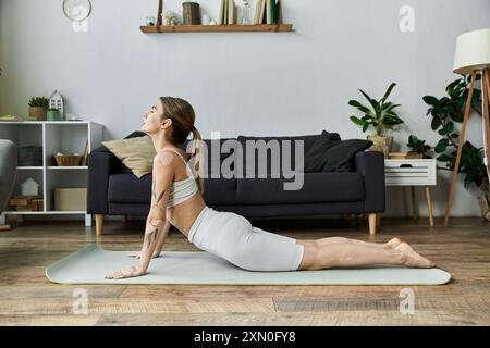 Une jeune femme en vêtements d'activité pratique le yoga sur un tapis dans un appartement moderne. Banque D'Images