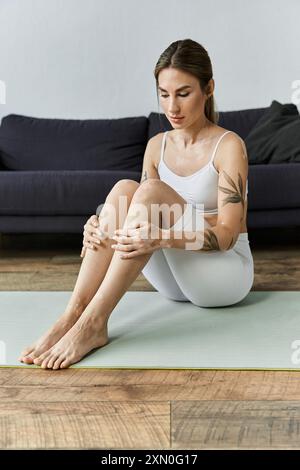 Une jeune femme atteinte de vitiligo médite sur un tapis de yoga dans un appartement moderne. Banque D'Images