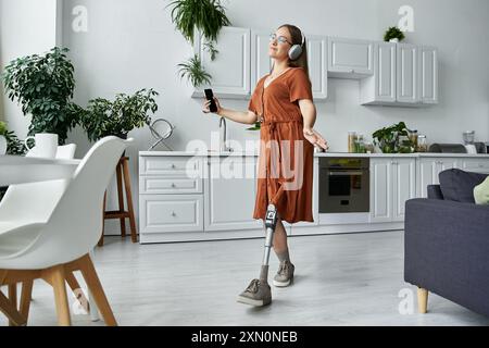 Une femme avec une jambe prothétique danse librement dans sa cuisine, profitant de la musique. Banque D'Images