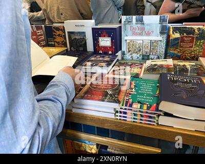 Pétersbourg, Russie, août 2021 : mains d'un homme feuilletant un livre en librairie parmi beaucoup d'autres livres et foules de gens. Banque D'Images