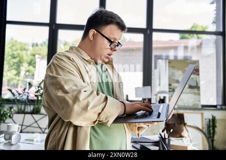 Un jeune homme atteint du syndrome de Down utilise un ordinateur portable dans un environnement de bureau. Banque D'Images
