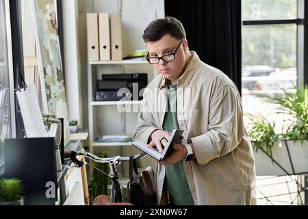 Un jeune homme atteint du syndrome de Down dans une chemise de couleur claire lit un livre tout en se tenant debout dans un bureau moderne. Banque D'Images