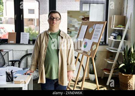 Un jeune homme atteint du syndrome de Down se tient confiant dans un espace de travail créatif. Banque D'Images