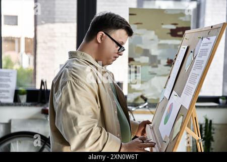 Un jeune homme atteint du syndrome de Down se tient près d'un tableau blanc, examinant une présentation. Banque D'Images