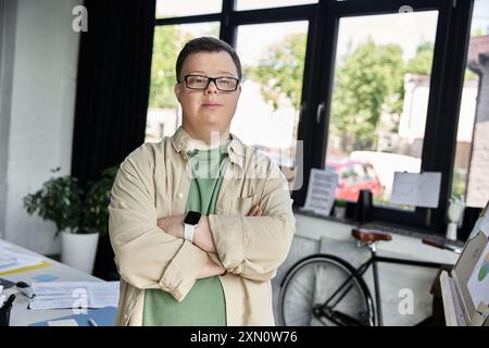 Le jeune homme atteint du syndrome de Down se tient confiant, les bras croisés, en chemise beige et en lunettes Banque D'Images