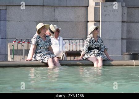 Londres, Royaume-Uni, 30 juillet 2024. Les visiteurs de Trafalgar Square se rafraîchissent près des fontaines tandis que le met Office enregistre 32 degrés celsius à Heathrow et Kew Gardens, ce qui en fait le jour le plus chaud de l'année jusqu'à présent. Crédit : onzième heure photographie/Alamy Live News Banque D'Images