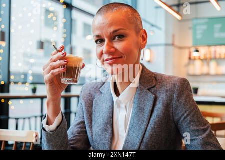 Femelle mature confiante buvant une tasse de café dans un restaurant. Une femme adulte moyenne se reposant et profitant d'une boisson de caféine sur une brèche de travail. Âge moyen Banque D'Images