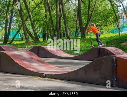 Moscou, Russie - 12 mai 2023 : une fille sur un scooter roule le long d'une piste de pompe de rue Banque D'Images