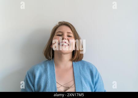 Jeune femme joyeuse de taille plus avec un large sourire debout sur fond blanc Uni. Banque D'Images