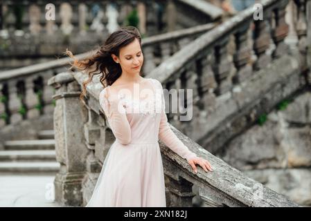 Une fille dans une robe rose clair contre le fond D'un château de pierre polonais médiéval Banque D'Images