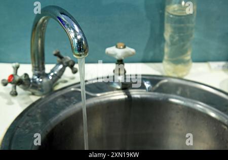 Vieux robinet en métal. L'eau s'écoule du robinet. Robinet métallique sale avec de l'eau qui coule dans l'évier de cuisine Banque D'Images