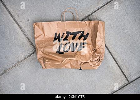Sac de transport en papier brun mis au rebut avec les mots « With Love » jonchant le trottoir à Édimbourg, en Écosse, au Royaume-Uni. Banque D'Images