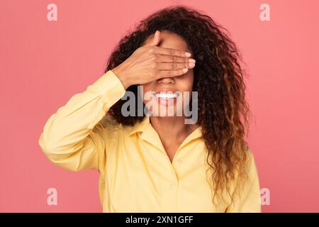Femme couvrant les yeux avec la main devant le fond rose Banque D'Images