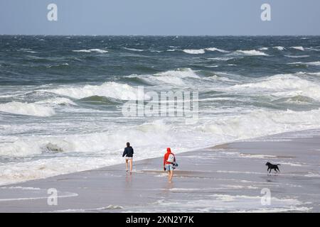 Stürmischer Spaziergang am Strand von Westerland, Sylt DEU, Deutschland, Sylt, Westerland : Das Bild zeigt zwei Personen, die Barfuß am Strand von Westerland auf Sylt spazieren. Die Nordsee ist rau und stürmisch mit hohen Wellen, die gegen die Küste schlagen. Westerland Sylt Schleswig Holstein Deutschland *** Stormy Walk on the Beach of Westerland, Sylt DEU, Allemagne, Sylt, Westerland L'image montre deux personnes marchant pieds nus sur la plage de Westerland sur Sylt la mer du Nord est agitée et orageuse avec de hautes vagues s'écrasant contre la côte de Westerland Sylt Schleswig Holstein Allemagne Banque D'Images