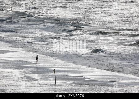 Einsamer Spaziergänger am stürmischen Strand von Westerland, Sylt DEU, Deutschland, Sylt, Westerland : Das Bild zeigt einen einsamen Spaziergänger am stürmischen Strand von Westerland auf Sylt. Die Nordsee zeigt sich mit starken, aufgewühlten Wellen, und der Himmel ist wolkenverhangen. Westerland Sylt Schleswig Holstein Deutschland *** marcheur solitaire sur la plage orageuse de Westerland, Sylt DEU, Allemagne, Sylt, Westerland la photo montre un marcheur solitaire sur la plage orageuse de Westerland sur Sylt la mer du Nord se montre avec des vagues fortes et agitées, et le ciel est nuageux Westerland Sylt Schleswi Banque D'Images