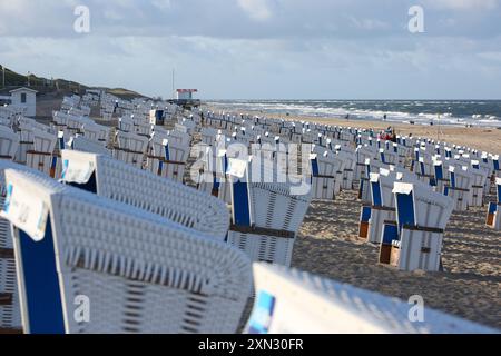 Strandkörbe am Strand von Westerland, Sylt DEU, Deutschland, Sylt, Westerland : Das Bild zeigt eine lange Reihe von Strandkörben am Strand von Westerland auf Sylt. Die Strandkörbe sind Weiß-blau und stehen geordnet auf dem Sand. IM Hintergrund ist das Meer mit seinen Wellen zu sehen und einige Personen spazieren am Strand entlang. Der Himmel ist leicht bewölkt. Westerland Sylt Schleswig Holstein Deutschland *** chaises de plage sur la plage de Westerland, Sylt DEU, Allemagne, Sylt, Westerland la photo montre une longue rangée de chaises de plage sur la plage de Westerland sur Sylt les chaises de plage sont blanches bl Banque D'Images