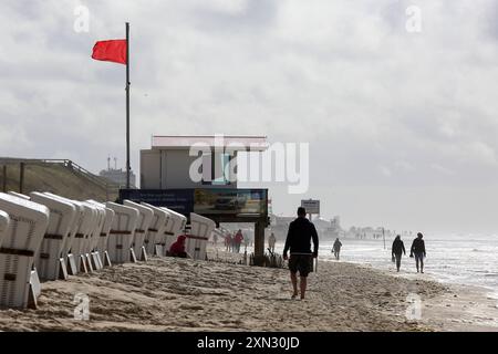 Strand von Westerland, Sylt - Baden verboten DEU, Deutschland, Sylt, Westerland : Das Bild zeigt einen Strandabschnitt in Westerland auf der Insel Sylt. IM Vordergrund sind mehrere weiße Strandkörbe in einer Reihe aufgestellt. Liens davon ist ein Rettungsturm mit einer roten Flagge, die darauf hinweist, dass das Baden verboten ist und Lebensgefahr besteht. Einige Personen spazieren entlang des Strandes. Der Himmel ist BEI stürmischen Wetter bewölkt. Westerland Sylt Schleswig Holstein Deutschland *** plage de Westerland, Sylt baignade interdite DEU, Allemagne, Sylt, Westerland L'image montre un Banque D'Images