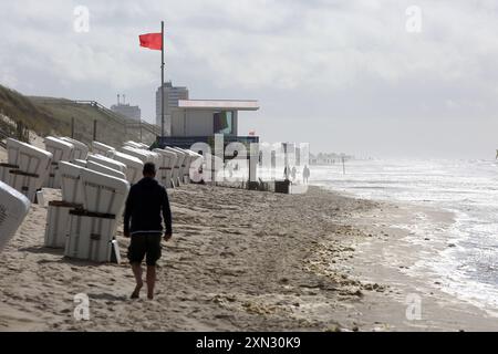 Strand von Westerland, Sylt - Baden verboten DEU, Deutschland, Sylt, Westerland : Das Bild zeigt einen Strandabschnitt in Westerland auf der Insel Sylt. IM Vordergrund sind mehrere weiße Strandkörbe in einer Reihe aufgestellt. Liens davon ist ein Rettungsturm mit einer roten Flagge, die darauf hinweist, dass das Baden verboten ist und Lebensgefahr besteht. Einige Personen spazieren entlang des Strandes. Der Himmel ist BEI stürmischen Wetter bewölkt. Westerland Sylt Schleswig Holstein Deutschland *** plage de Westerland, Sylt baignade interdite DEU, Allemagne, Sylt, Westerland L'image montre un Banque D'Images