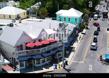 Une scène de rue animée dans une charmante ville côtière avec des bâtiments colorés, un restaurant de fruits de mer avec des parasols rouges, et piétons animés et v Banque D'Images