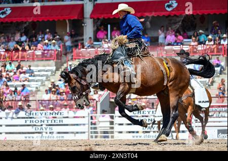 Un cow-boy tente de s'accrocher à un cheval pendant au moins huit secondes lors d'une promenade en selle bronc à Cheyenne Frontier Days, Cheyenne, Wyoming, le 25 juillet 2024. Depuis sa création en 1897, Cheyenne Frontier Days est devenu une célébration emblématique de la culture occidentale, offrant un mélange unique de compétitions de rodéo, de spectacles et de reconstitutions historiques qui attirent des visiteurs du monde entier. (Photo de l'US Air Force par Airman 1st Class Mattison Cole) Banque D'Images