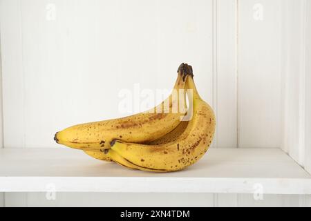 Bouquet de bananes mûres avec des taches sombres sur l'étagère Banque D'Images