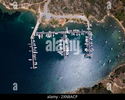 Vue aérienne d'une marina à Sithonia, en Grèce, avec de nombreux bateaux et yachts amarrés aux quais, capturant la beauté organisée et l'activité vibrante Banque D'Images