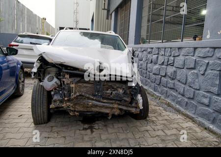 Une voiture blanche, gravement endommagée lors d'une collision, se trouve abandonnée dans une rue de la ville, un rappel brutal de l'impact des accidents. Banque D'Images