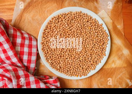 Assiette de pois chiches avec du papier cuisson brûlé et un tissu à carreaux rouge sur la table Banque D'Images